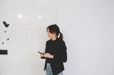 Mid adult businesswoman holding felt tip pen while standing in creative office