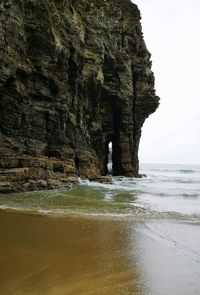 Rock formation on beach against sky