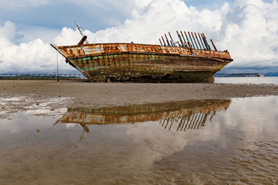 Abandoned boat moored at beach