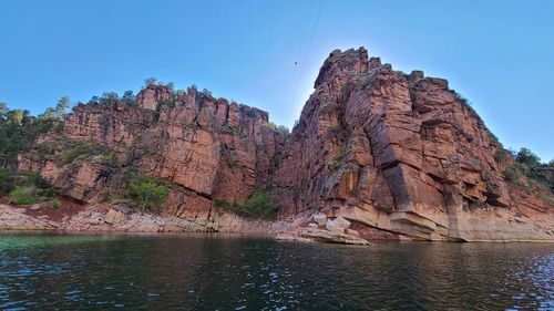 Rock formations in water against sky