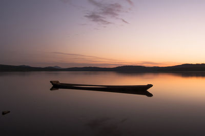 Silhouette boat in lake against sky during sunset