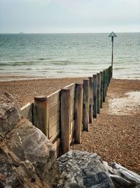 Wooden posts on beach against sky