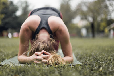 Woman practicing headstand on grassy field