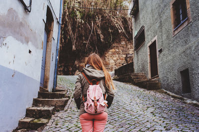 Rear view of woman standing on street amidst buildings