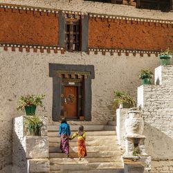 Sisters walking on steps against house