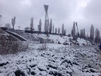 Snow covered field against cloudy sky