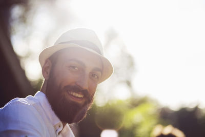 Low angle portrait of happy man wearing fedora on sunny day