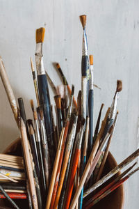 Close-up of paintbrushes in container on table against wall