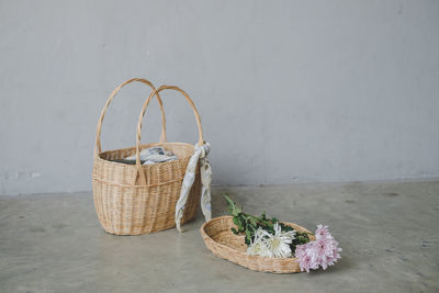 Close-up of white flowers in basket on table against wall