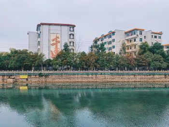 Buildings by lake against sky in city