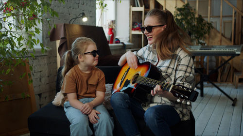 Mother teaching guitar to daughter