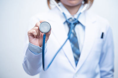 Midsection of female doctor with stethoscope against white background