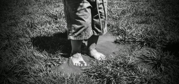 Low section of boy standing in muddy water