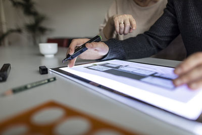 Close-up of man using tablet with architectural plan