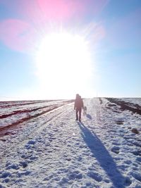 Rear view of man walking on snow covered landscape