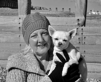 Portrait of woman holding dog while standing at beach