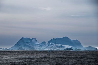 Scenic view of iceberg by sea against sky