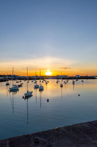 Boats moored in marina at sunset