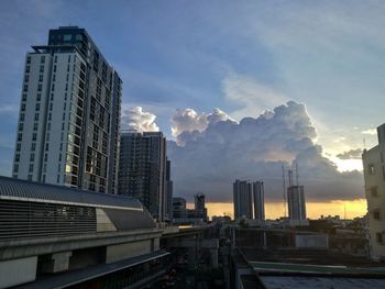 Modern buildings in city against sky during sunset