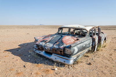 Wreck of abandoned vintage car against clear blue sky in namib desert of angola, africa