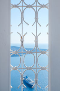 Close-up of metal fence against sky seen through window