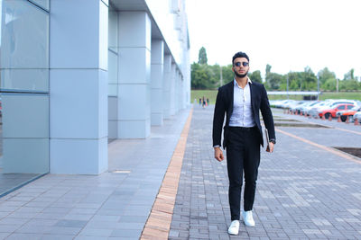 Young businessman standing against building