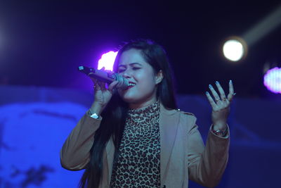 Young woman with arms raised standing at music concert