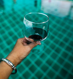 Midsection of man holding glass of swimming pool