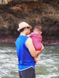 Enjoying holiday in a beautiful beach. father and son are relaxing when the sea water is rising.