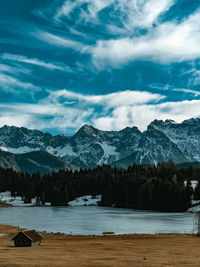 Scenic view of lake by snowcapped mountains against sky