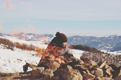 Man standing on rock by snowcapped mountains against sky