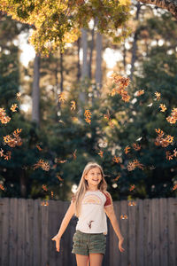 Portrait of young woman standing by tree