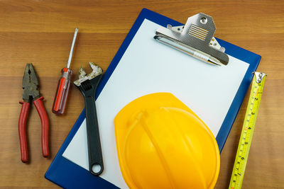 High angle view of hand tools with hardhat and clipboard