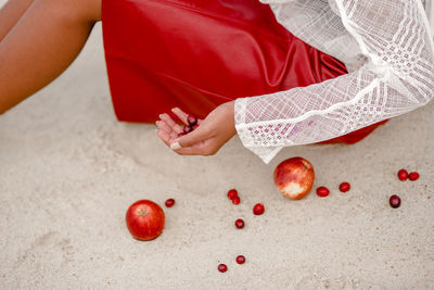 Midsection of woman holding fruit on sand