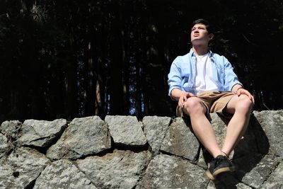 Young man sitting on rock