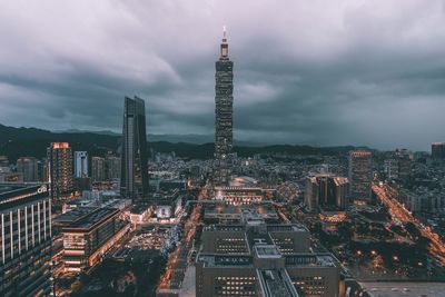 Illuminated cityscape against cloudy sky