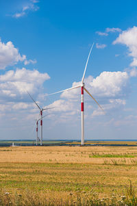 Windmills on field against sky