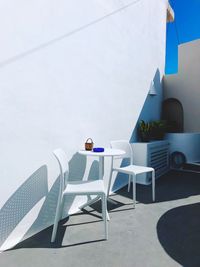 Empty chairs and tables against building