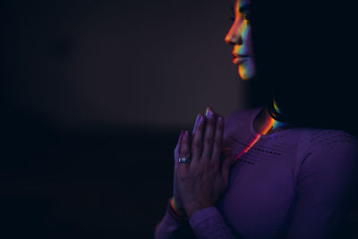 Midsection of woman meditating in darkroom