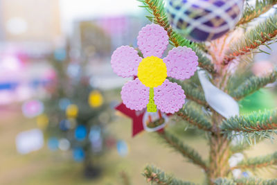 Handmade plastic pink flower decoration on christmas tree outdoors. diy ceative ideas for children