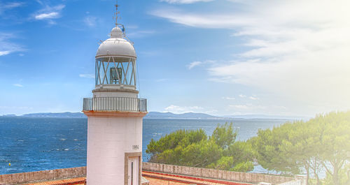 Roses lighthouse against blue sky with white clouds on northern coast spain