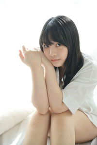 Portrait of young woman sitting against white background