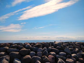 Stack of rocks by sea against sky