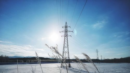 Electricity pylon against sky during winter