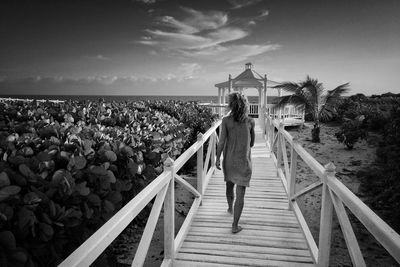 Rear view of woman standing on railing