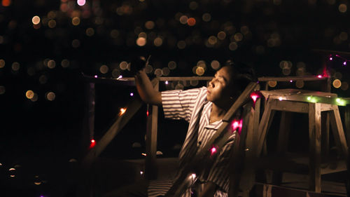 Young man looking away while sitting at night