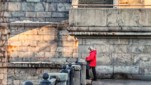 Side view of woman standing by wall