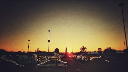 Vehicles on road against sky at sunset