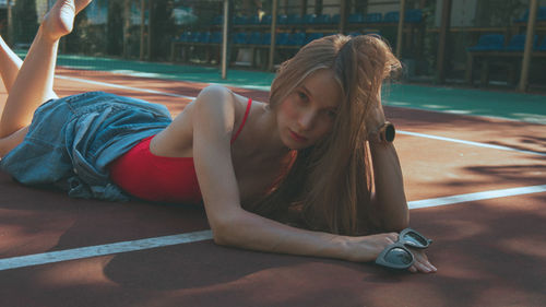 Portrait of young woman lying on court