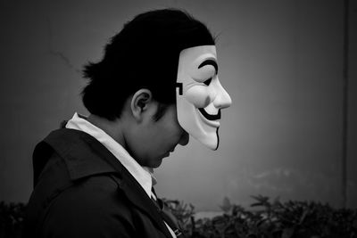 Black and white portrait of a person wearing a mask looking down